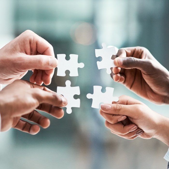 Hands joining puzzle pieces together, symbolising partnership